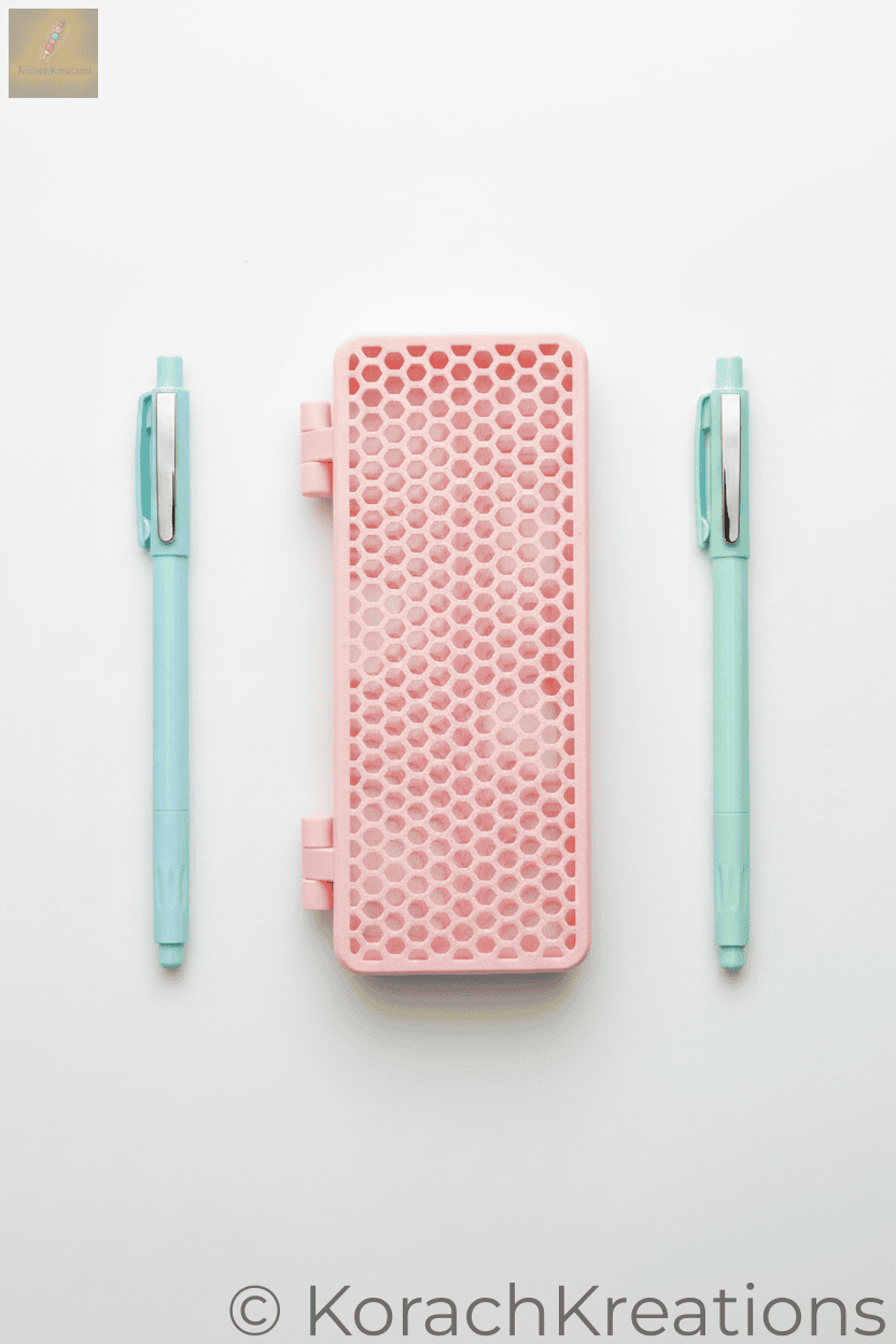Pink honeycomb mesh pencil case closed with a pen on each side